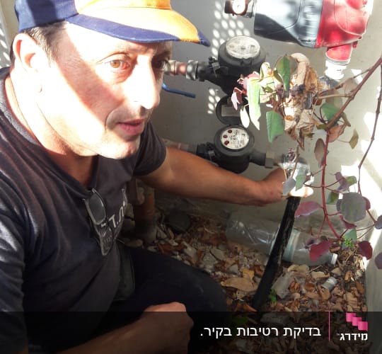 אדם בודק צינור מים עם מד מים